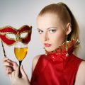 Portrait of beautiful  young women with wine holding red carnival mask